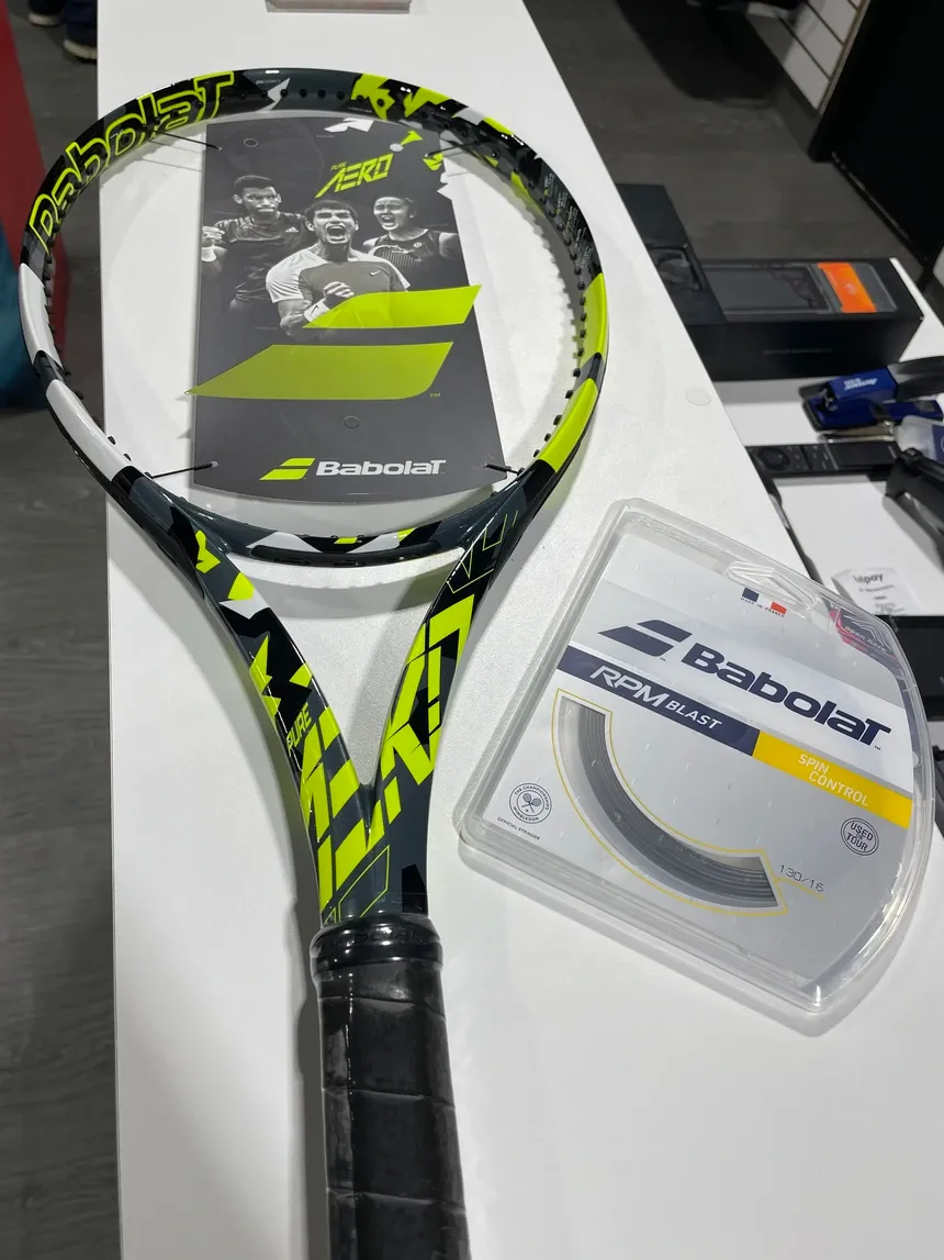 Tennis racket next to a pack of Babolat strings